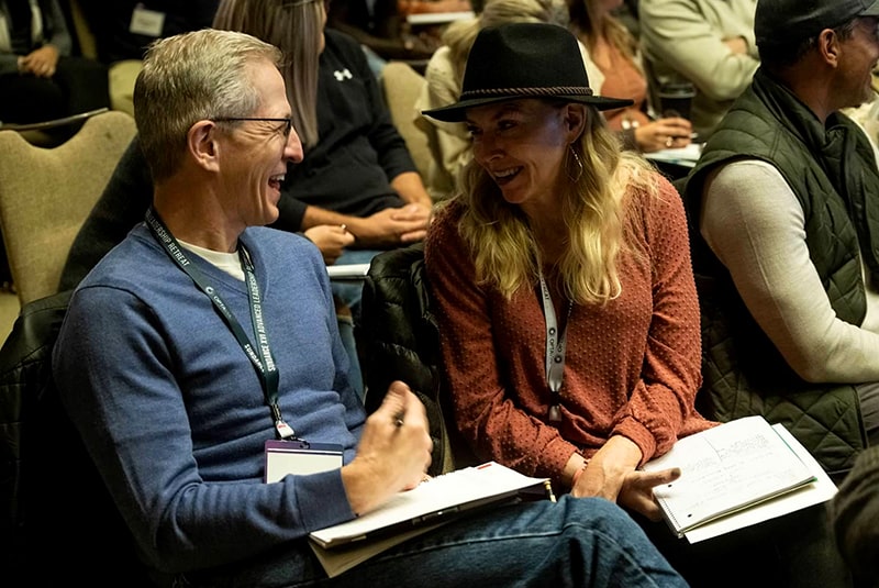 Man and woman Coaches talking to each other during a session, smiling.